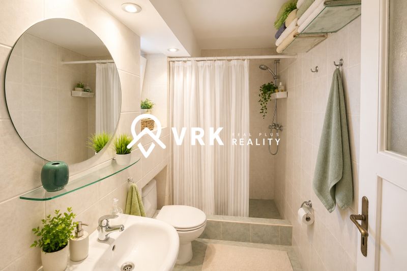 Bathroom in a family house with a sink, mirror, shower corner, and curtain.