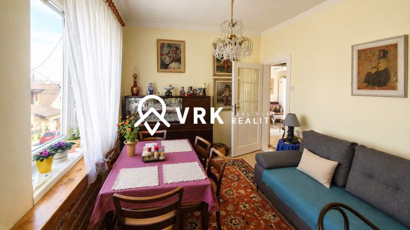 Living room in a family house with flowers on the windowsill and an impressive chandelier.
