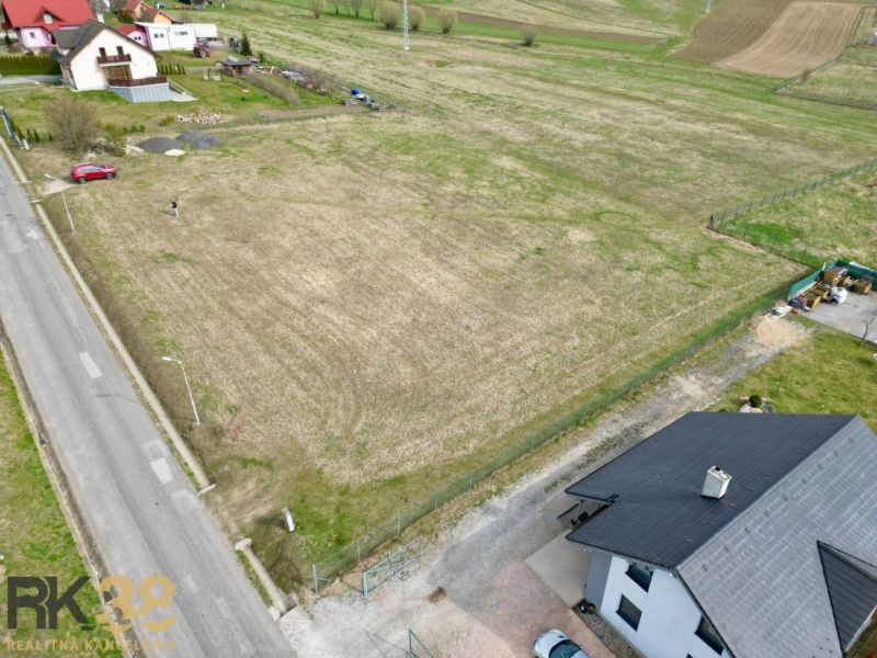 Plots - housing in the village of Vlková, showing an open grassy area bordered by a road and houses.