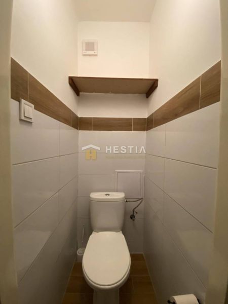 Bathroom in a 2-room apartment with practical white toilet and wooden decor.