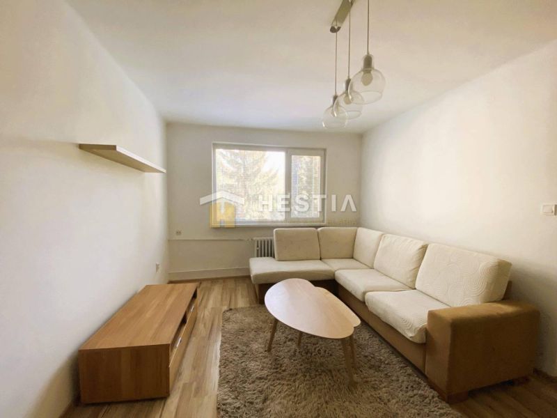Living room with a beige corner sofa, wood-patterned flooring, and a wall shelf.