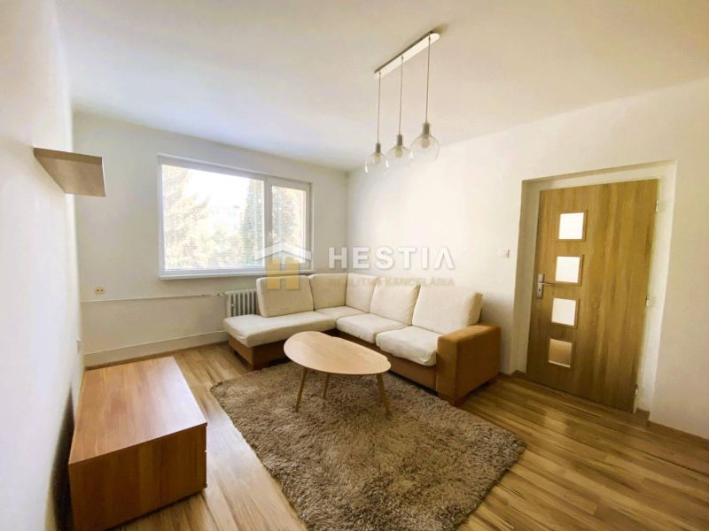 Living room in a two-room apartment with a wood-patterned floor and a light-colored sofa.