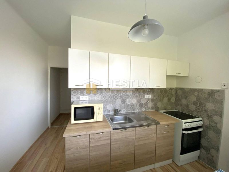 Kitchen in a 2-room apartment with a wooden decor floor and gray tiles.