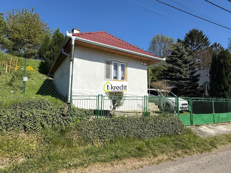 A family house in Čaradice with a red roof and green gates in the garden.