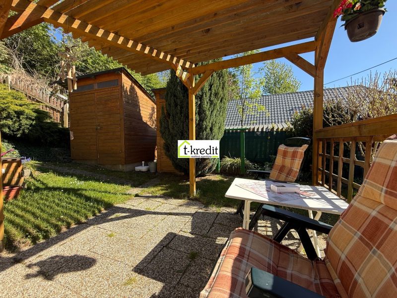 A garden at a family house in Čaradice with a pergola and a wooden cottage.