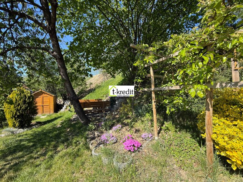 The garden of a family house in Čaradice with a gazebo and a wooden house on a grassy area.