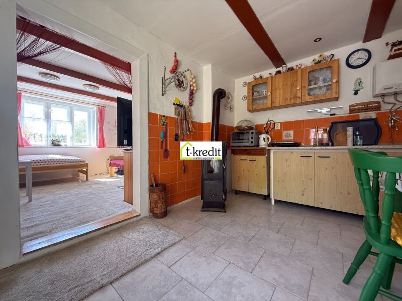 A kitchen in a family house with a stove and a passage to a bright living room.