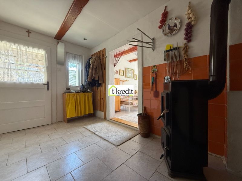 Interior of a family house with a tiled stove, wooden decor flooring, and a hanging storage system.
