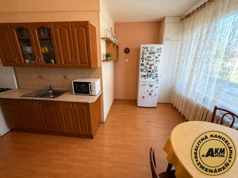 A kitchen in a 3-room apartment with a wood-patterned floor and a dining area.