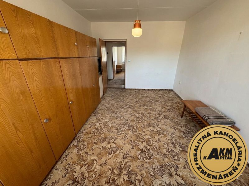 A room with a carpet, wooden cabinets, and a table, a 3-room apartment.