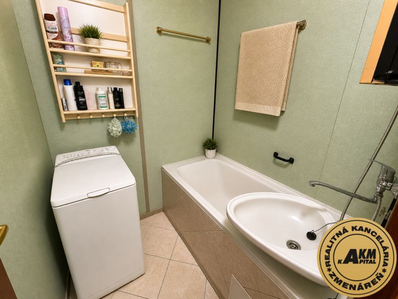 Bathroom with a bathtub, washing machine, and a shelf with containers in a 3-room apartment.