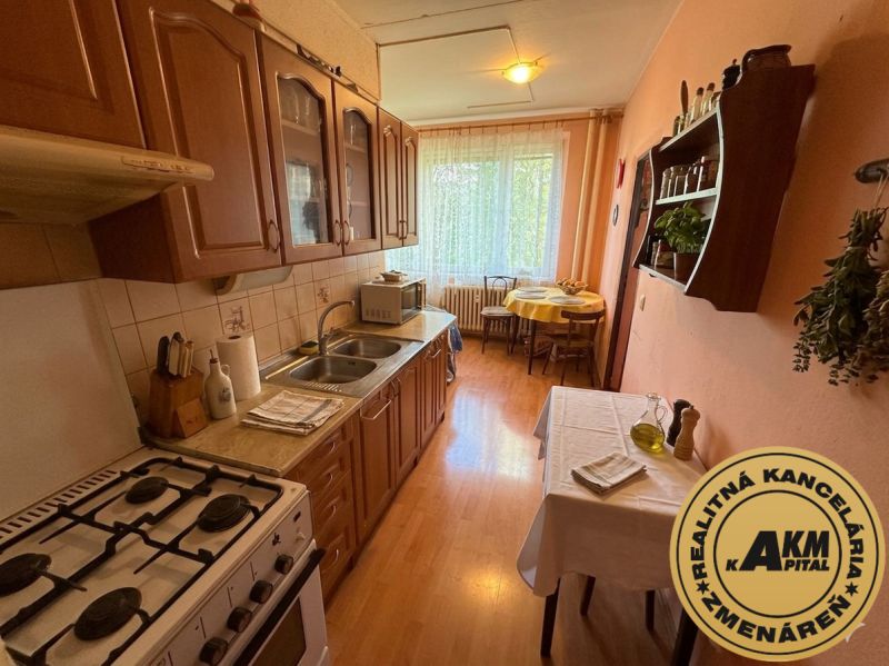 A kitchen in a 3-room apartment with a wooden decor floor, equipped with a gas stove.