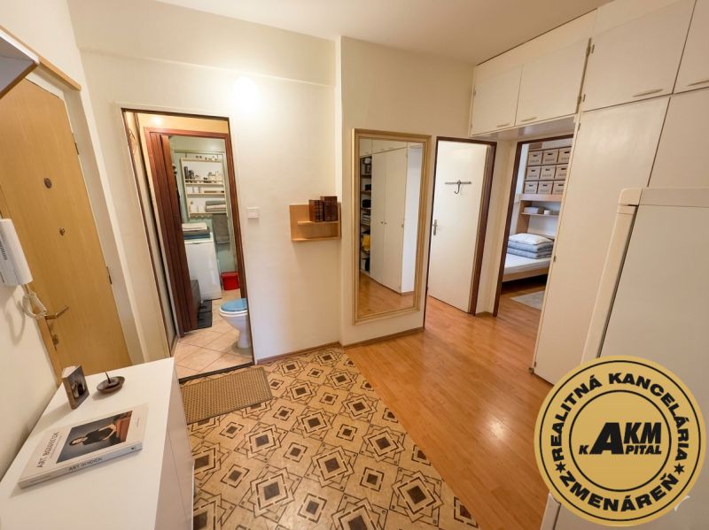 The hallway in a 3-room apartment with a wooden decor floor and entrance to the bathroom.