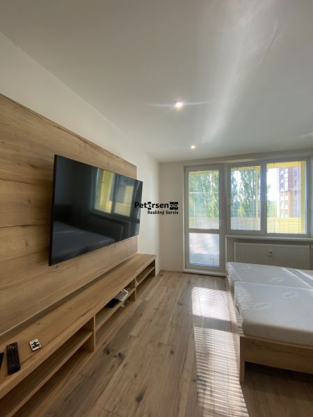 Bedroom in a 2-room apartment with a built-in TV and a floor with a wooden decor.