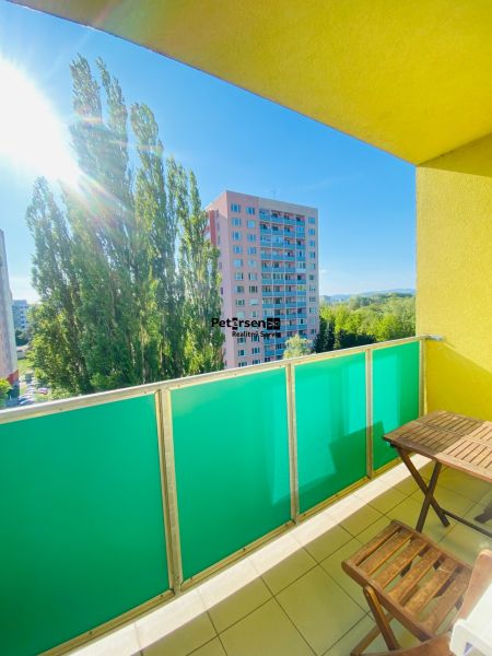 The balcony of a 2-room apartment with a view of panel buildings and trees in Košice, Nad jazerom district.