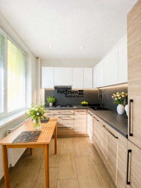 A kitchen in a 2-room apartment with a wooden decor floor and white cabinets.