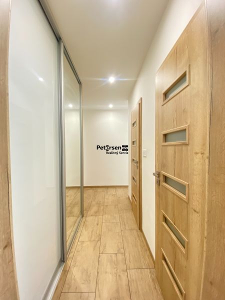 A hallway in a 2-room apartment with a wooden decor floor and built-in wardrobes.