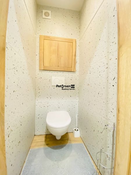 Toilet room in a 2-room apartment with wood-patterned tiles and flooring.