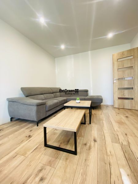 Living room in a two-room apartment with a corner sofa and a floor with a wooden decor.