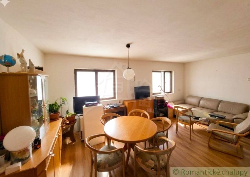Living room with a sofa, windows, table, and wooden decor flooring in a family house.