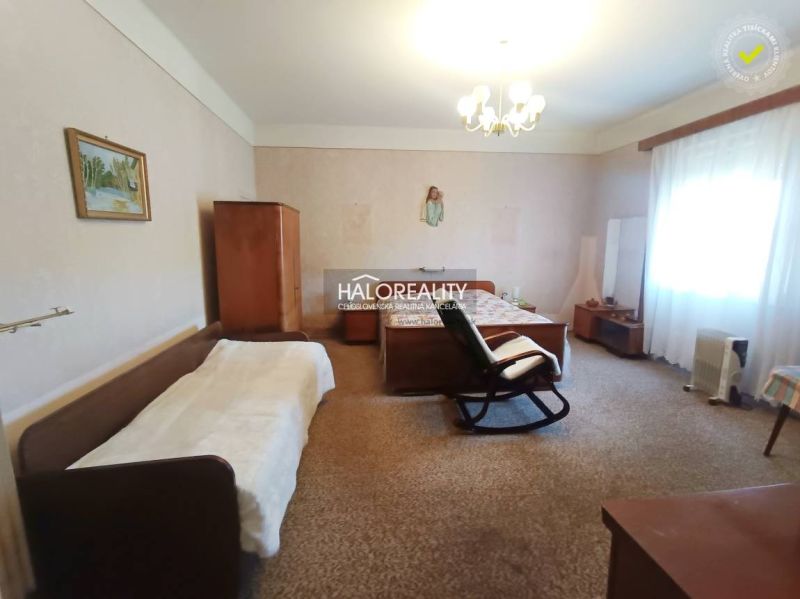A bedroom in a 2-room apartment with a carpet, bed, chair, and wardrobes.