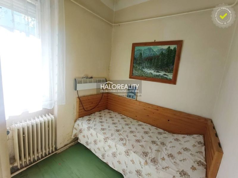 A simple room in a 2-room apartment with a bed, a picture, and a window with a radiator.