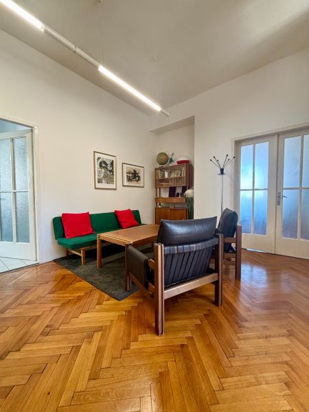 Offices with wooden decor, sofa, armchair, and table. There are paintings on the wall.