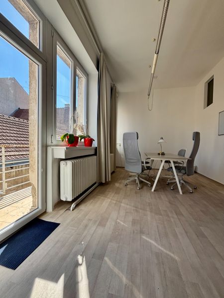 Offices with wood-patterned flooring, a table, and chairs by the windows.