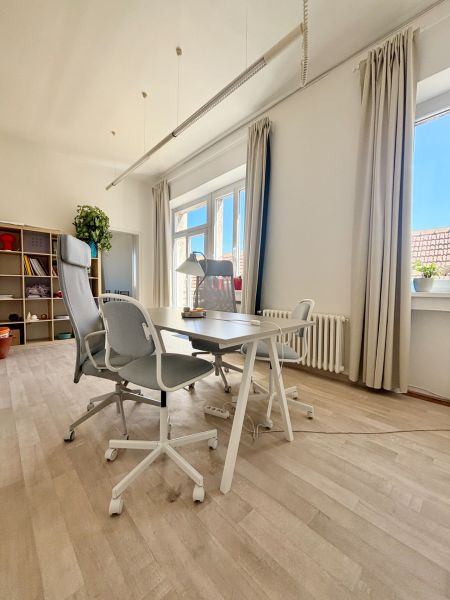 Offices with large windows, a desk and chairs, and a floor with a wooden decor.