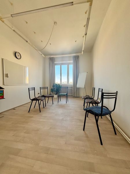 Office with wood-patterned flooring, six chairs, a board, and a window.