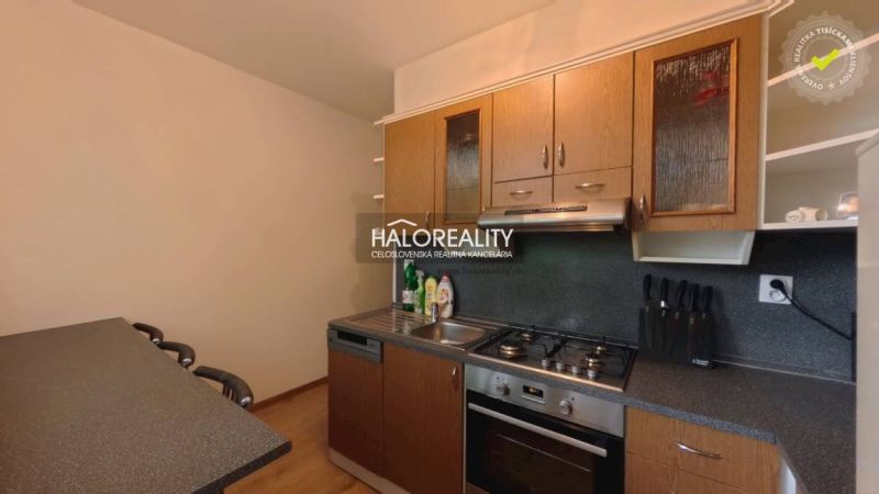 A kitchen in a 2-room apartment with a wooden decor floor and a kitchen unit.