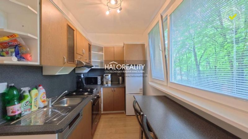 A kitchen in a 2-room apartment with a wooden decor and a large window overlooking greenery.