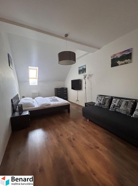Bedroom with a bed and a sofa, wooden decor flooring in a two-room apartment.