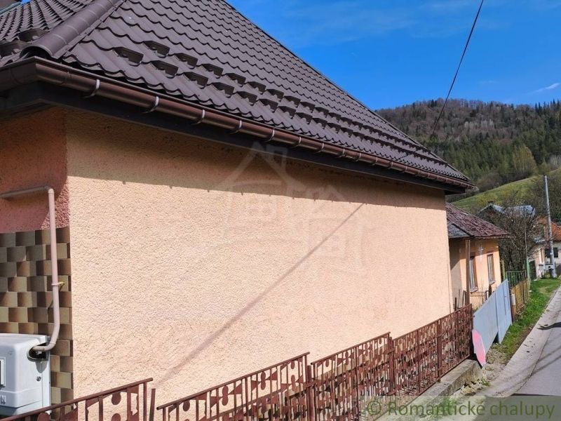 A family house in Reľov with a brown roof and a massive fence.