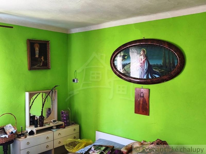 A room in a family house with distinctly green walls and religious paintings.