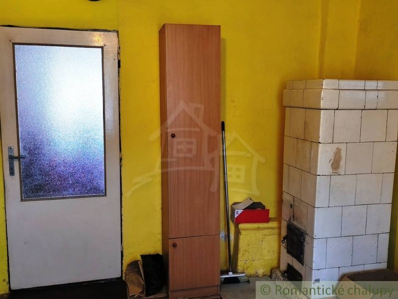 Yellow wall with a tiled stove, door, and wardrobe in a family house.