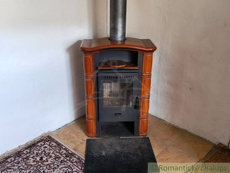 A tiled stove in the corner of a family house with tiles and a carpet pad.