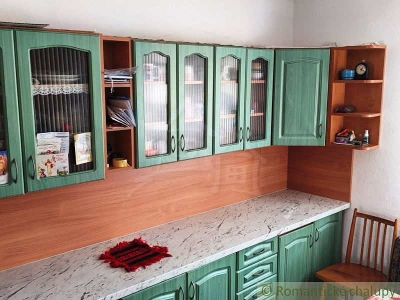 A kitchen unit in a family house with green doors and a marble countertop.
