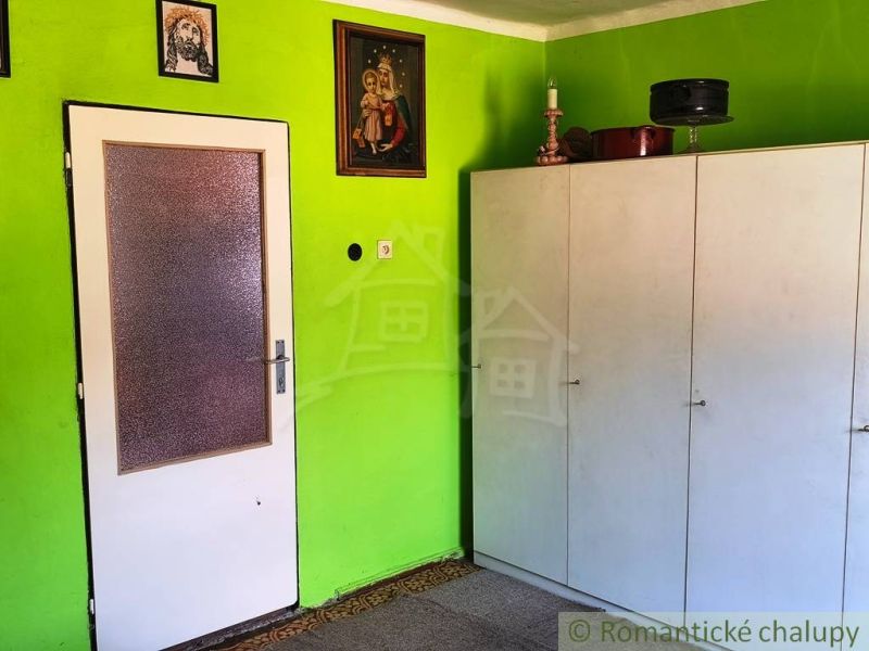 Interior of a family house with a white cabinet and a green wall with icons.