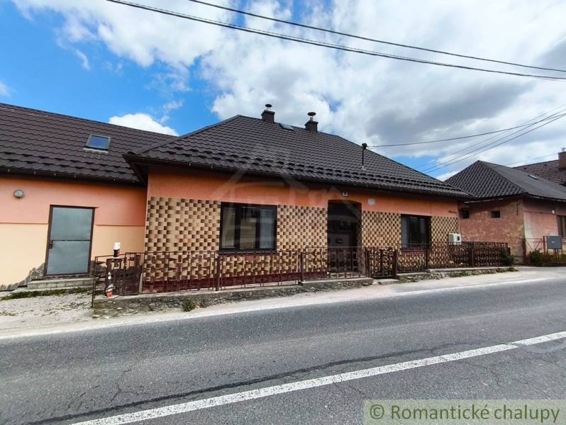 A family house in Reľov with brick cladding and a sloped metal roof.