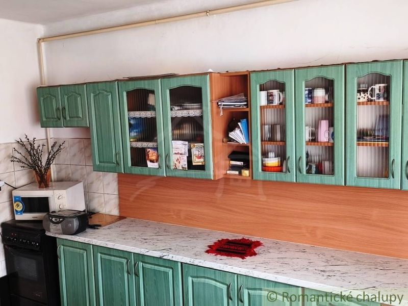 Green kitchen in a family house with a marble countertop and ceramic tiles.