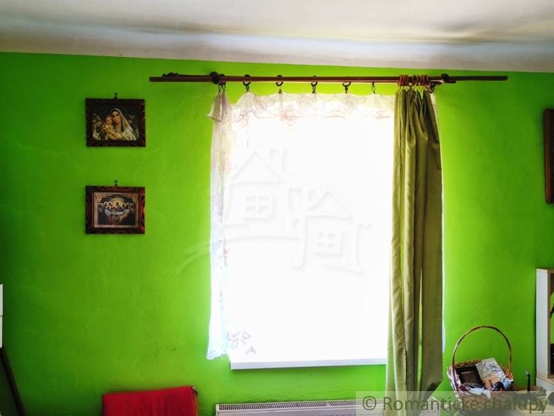 A room in a family house with bright green walls, a curtain, and wall paintings.