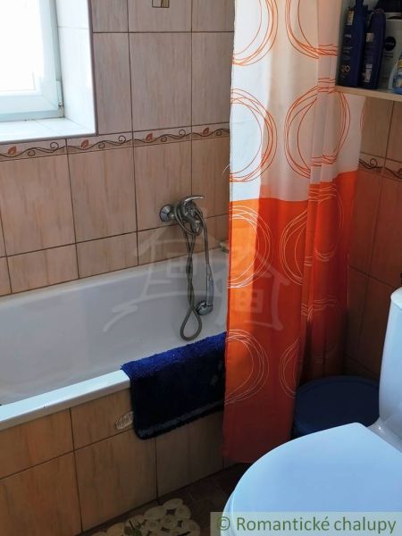 A bathroom in a family house with a shower curtain and a bathtub, ceramic tiles.