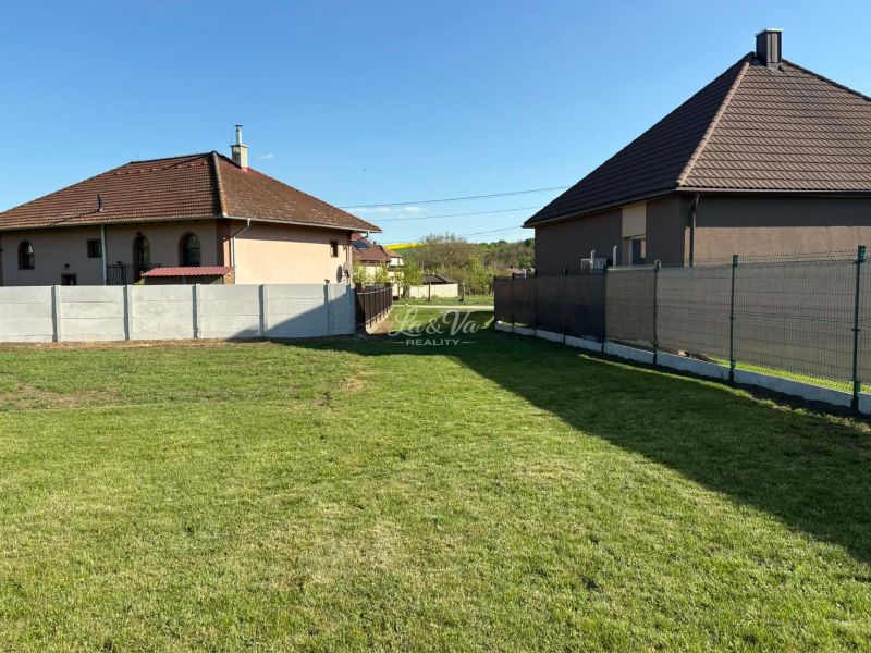 A peaceful garden, surrounded by houses and fences in Pozba, ideal for residential plots.