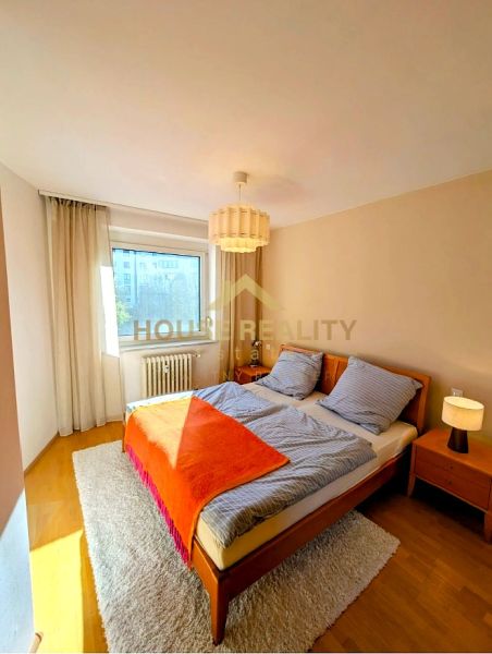 A bright bedroom in a 4-room apartment with a double bed and a wooden decor floor.