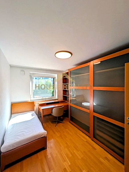 A room with furniture, a bed, a table, a wardrobe, and a floor with a wooden decor in a 4-room apartment.