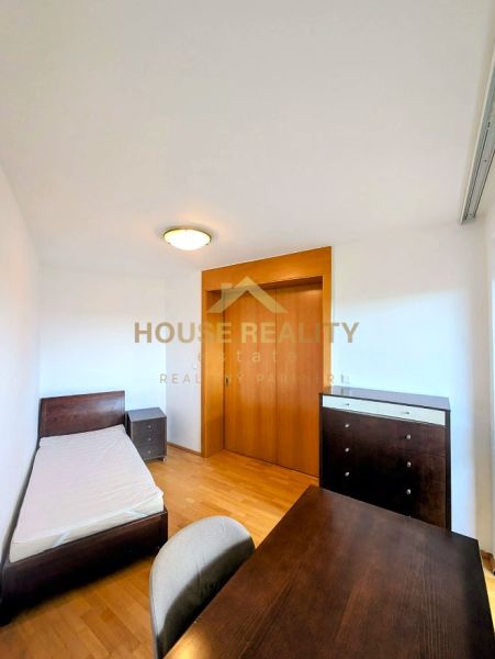 A room with a bed, a table, and a wardrobe in a 4-room apartment with a wooden decor floor.