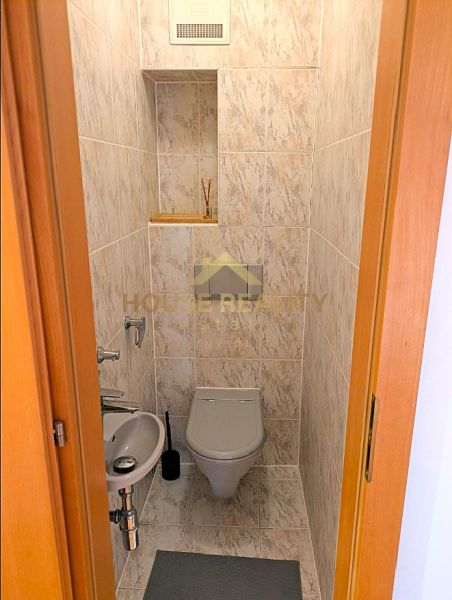 A toilet with a sink in a 4-room apartment, tiled with light ceramic tiles.