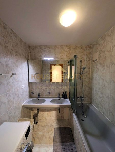 A bathroom with a bathtub and two sinks in a 4-room apartment with a washing machine.