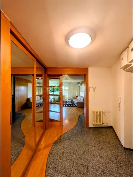 A hallway of a 4-room apartment with a wooden decor floor and built-in wardrobes.